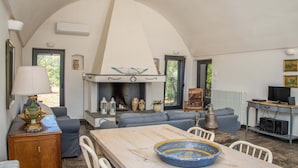A spacious living room with a high arched ceiling, a fireplace, a dining table, and comfortable seating. - 3598 Trullo Yoram by Perle di Puglia (Francavilla Fontana)