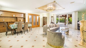 A spacious living area with a dining table, cushioned seating, and a chandelier. - 3602 Villa Asia by Barbarhouse (Fasano)