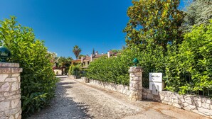 A gravel driveway leading to a stone wall with a mailbox. - 3602 Villa Asia by Barbarhouse (Fasano)