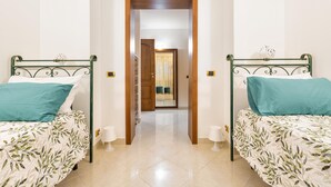 A hotel room with two single beds, a wooden door, a hallway, and a view into another room. - 3602 Villa Asia by Barbarhouse (Fasano)