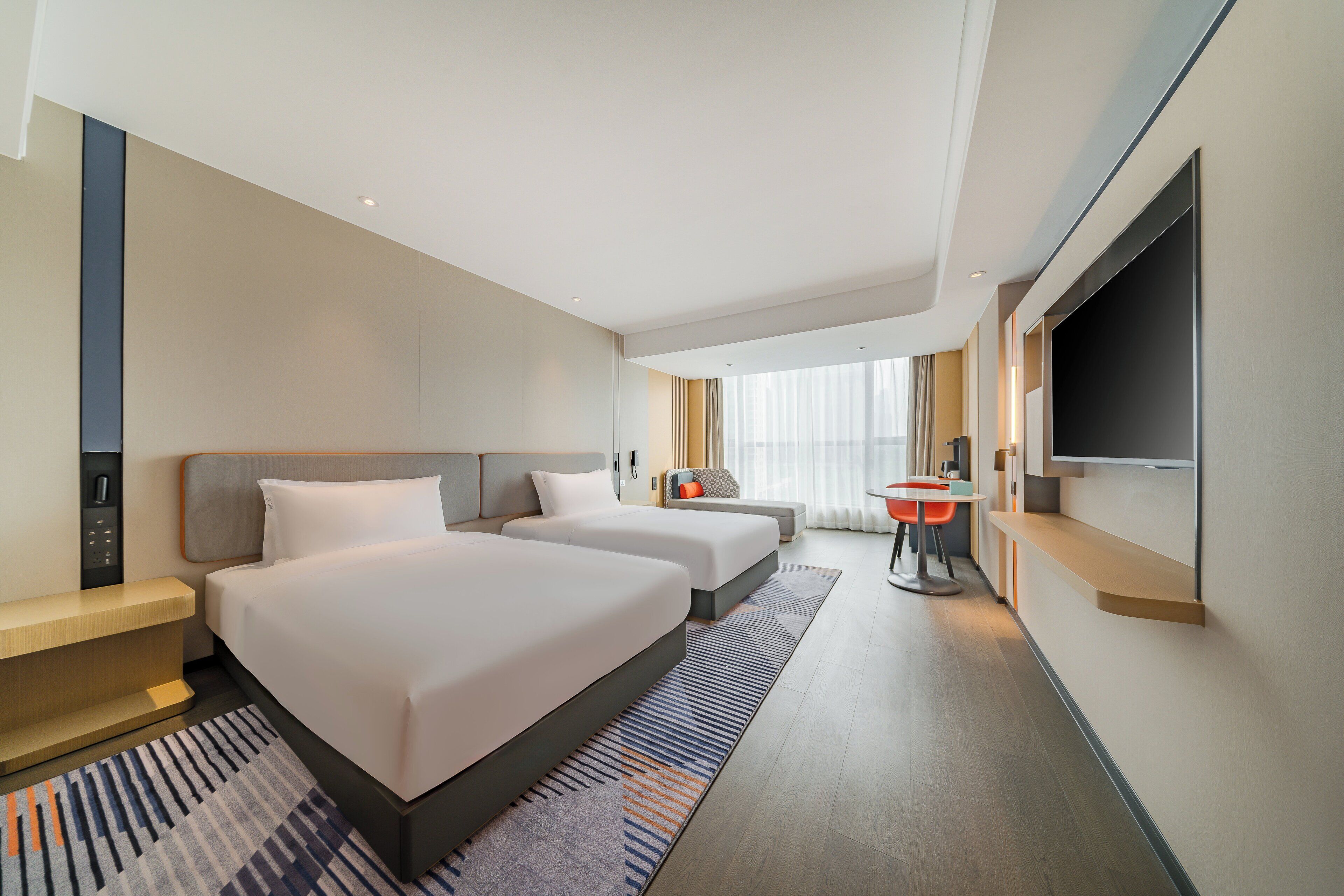 Een hotelkamer met twee bedden, een bureau, een televisie en een badkamer.