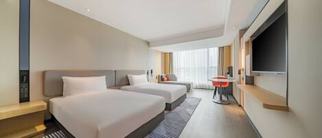 Een hotelkamer met twee bedden, een bureau, een televisie en een badkamer.