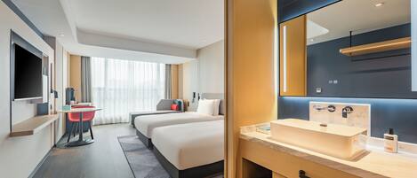Une chambre d’hôtel avec un grand lit, un bureau avec une chaise, une télévision et une salle de bain équipée d’un lavabo et d’un miroir.