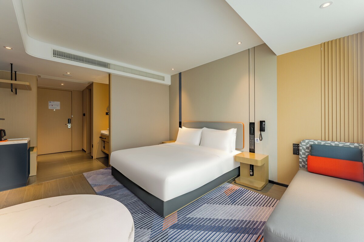 Een moderne hotelkamer met een groot bed, nachtkastjes, een bureau en een badkamer.