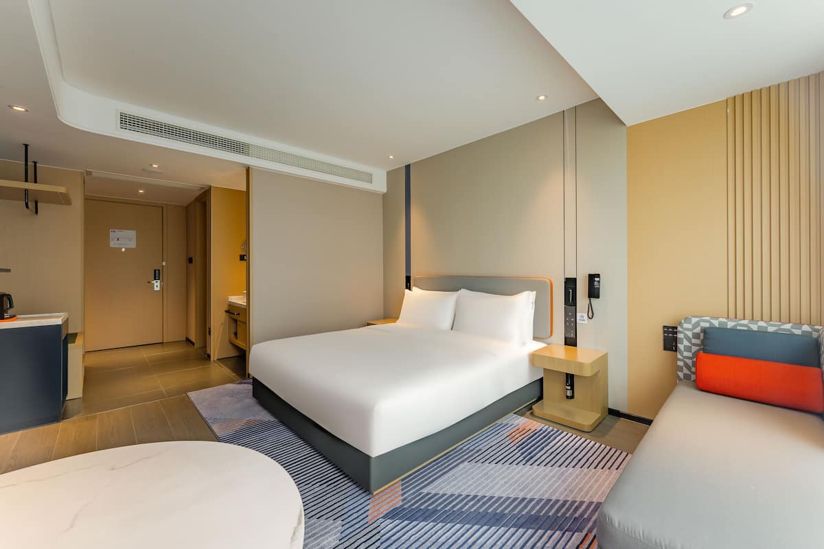 Una habitación de hotel moderna con una cama grande, mesitas de noche, un escritorio y un baño.