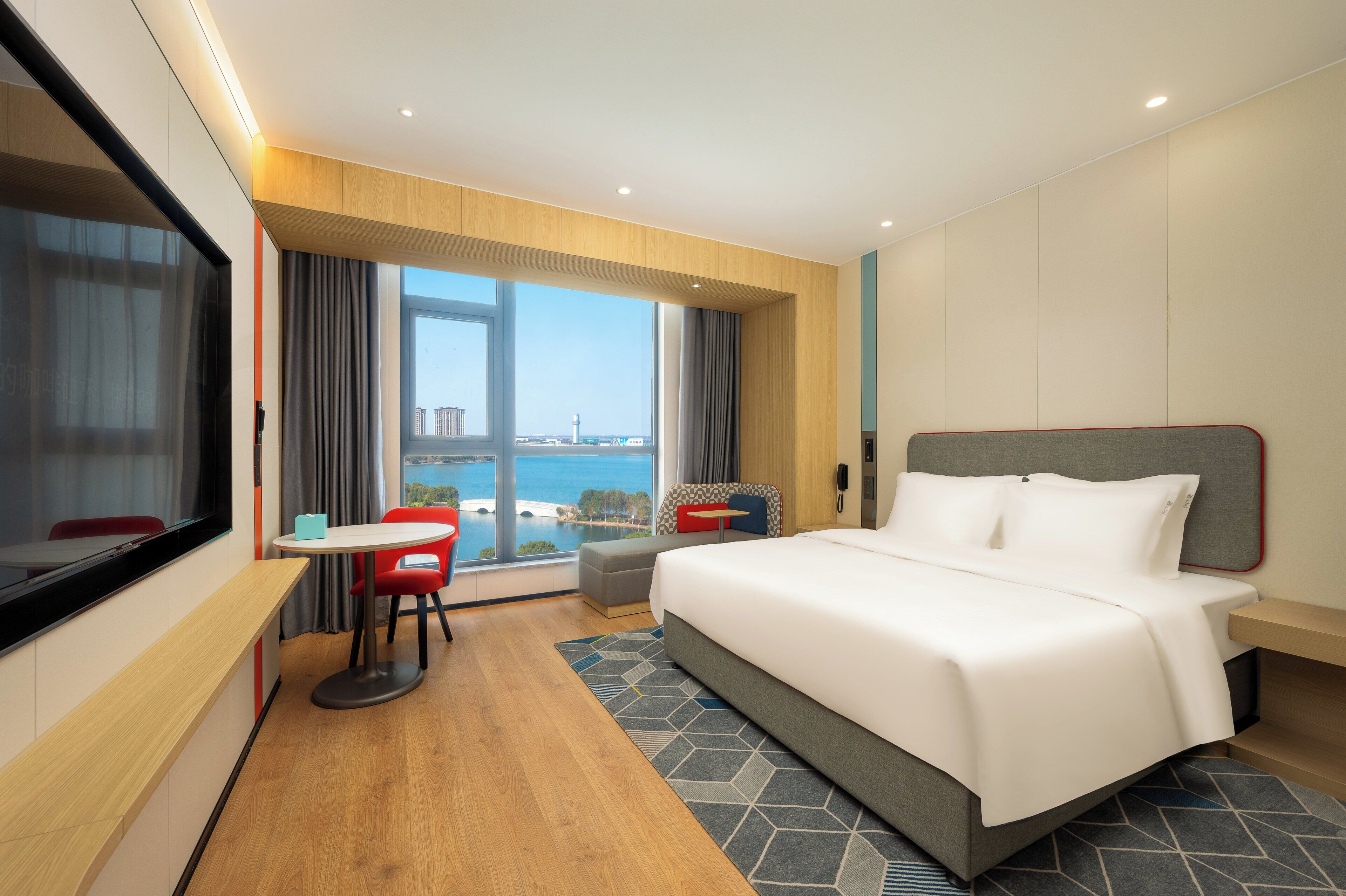 Une chambre d’hôtel dotée d’un grand lit, d’un bureau avec une chaise, d’une vue sur la mer et d’un design moderne.