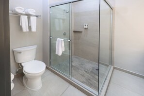 A modern bathroom with a glass-enclosed shower, a toilet, and a towel rack with towels.