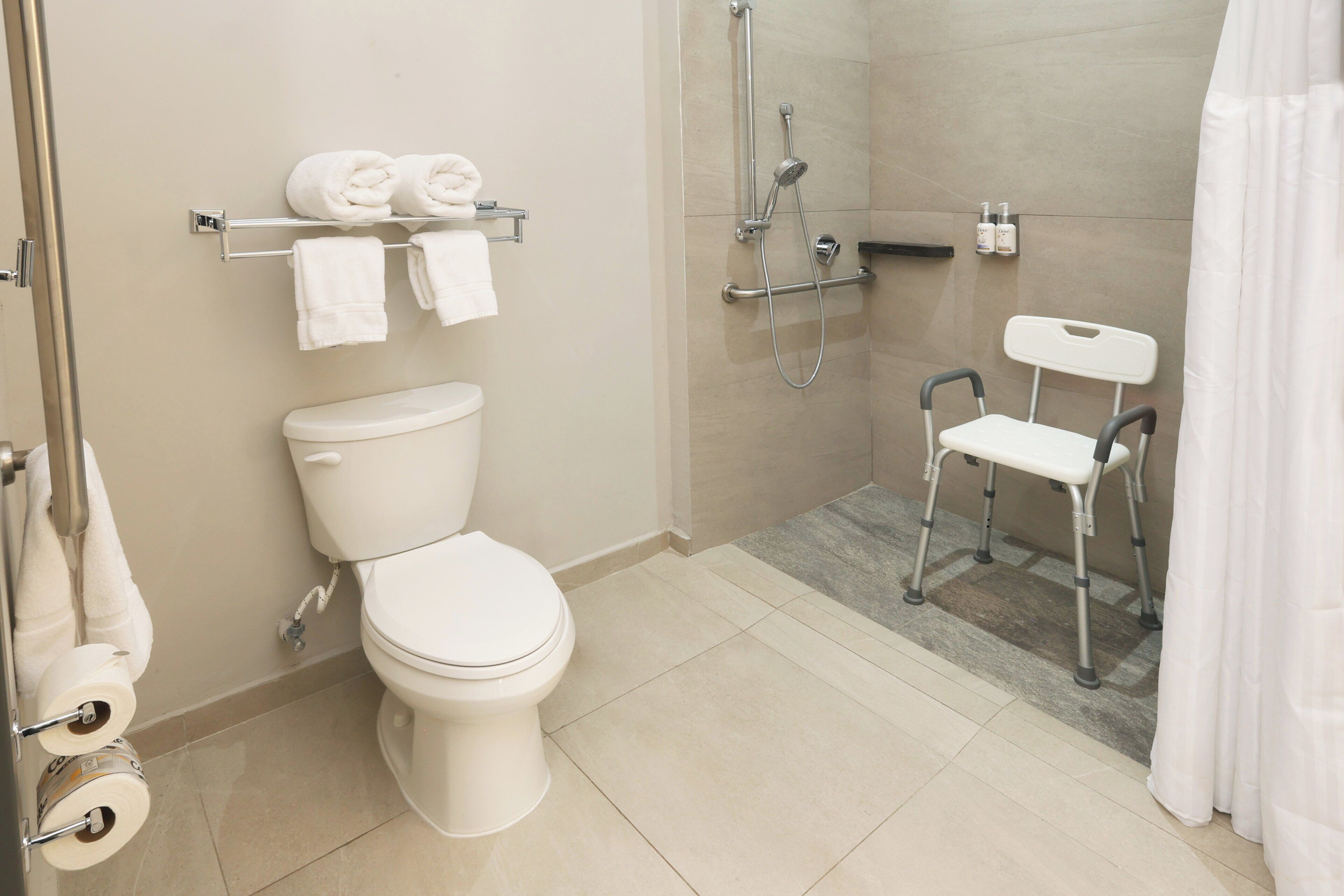 Un baño moderno con inodoro, ducha y barra de apoyo.
