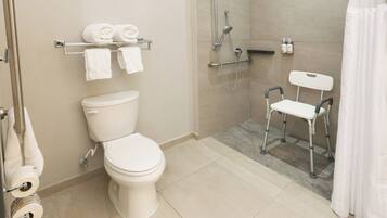 Un baño moderno con inodoro, ducha y barra de apoyo.