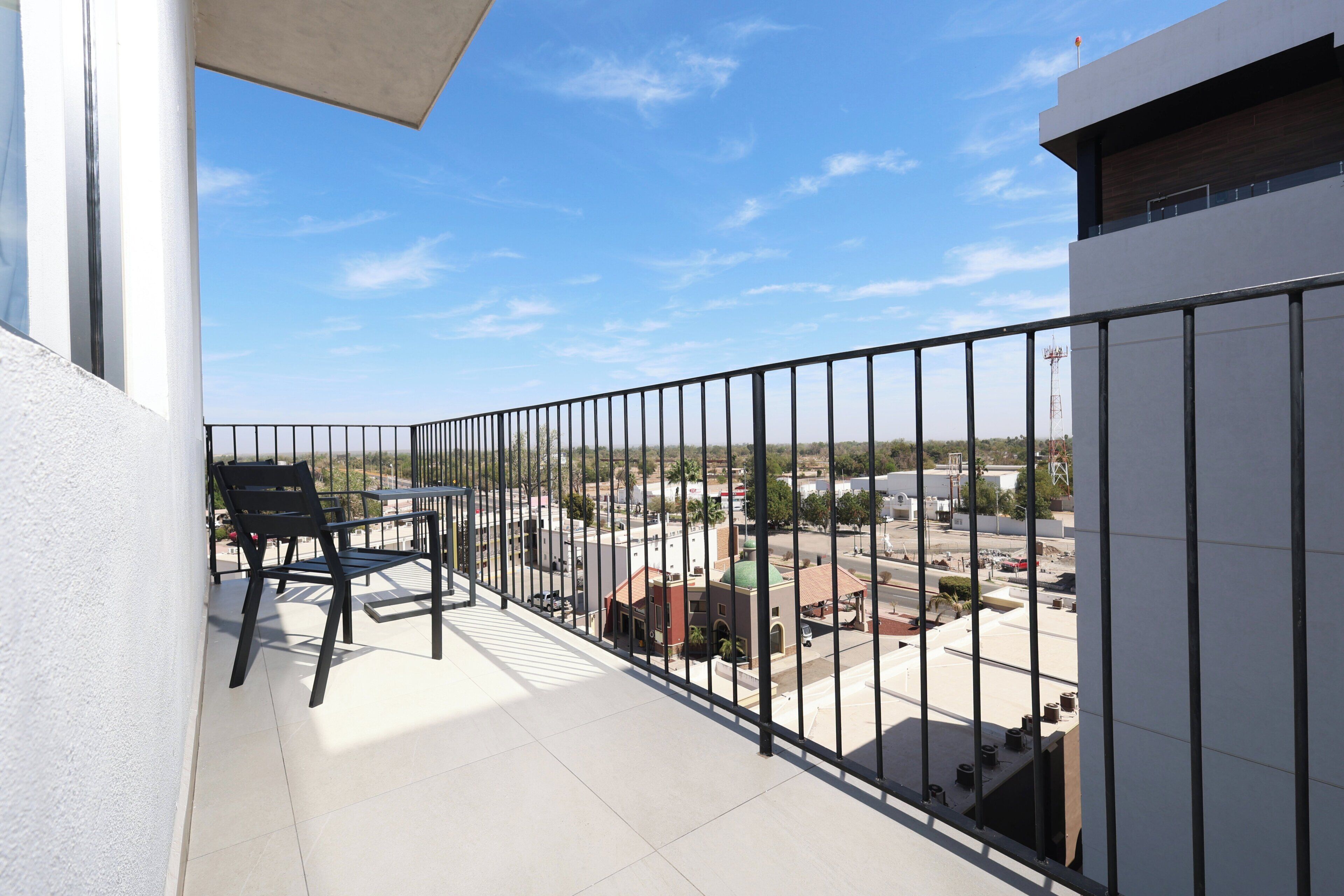 A balcony with a black metal railing, a table, and two chairs.