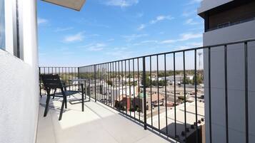 A balcony with a black metal railing, a table, and two chairs.