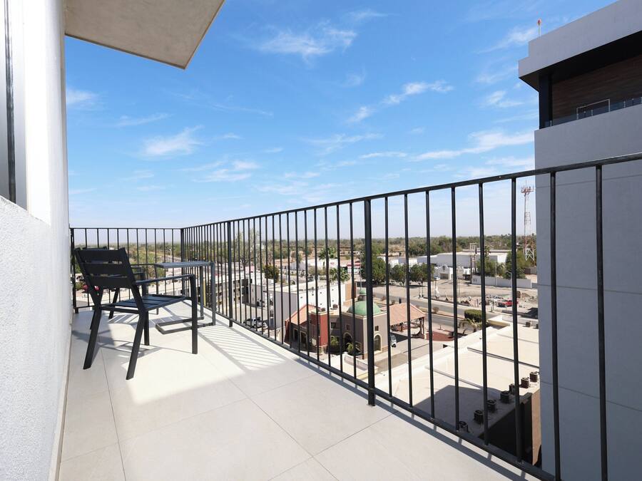 A balcony with a black metal railing, a table, and two chairs.