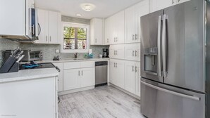 A modern kitchen with white cabinets, stainless steel appliances, and a dishwasher. - Lulu's Crescent Cottage #1 (Siesta Key)