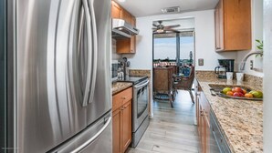Una cucina moderna con elettrodomestici in acciaio inox, mobili in legno e vista all'esterno.