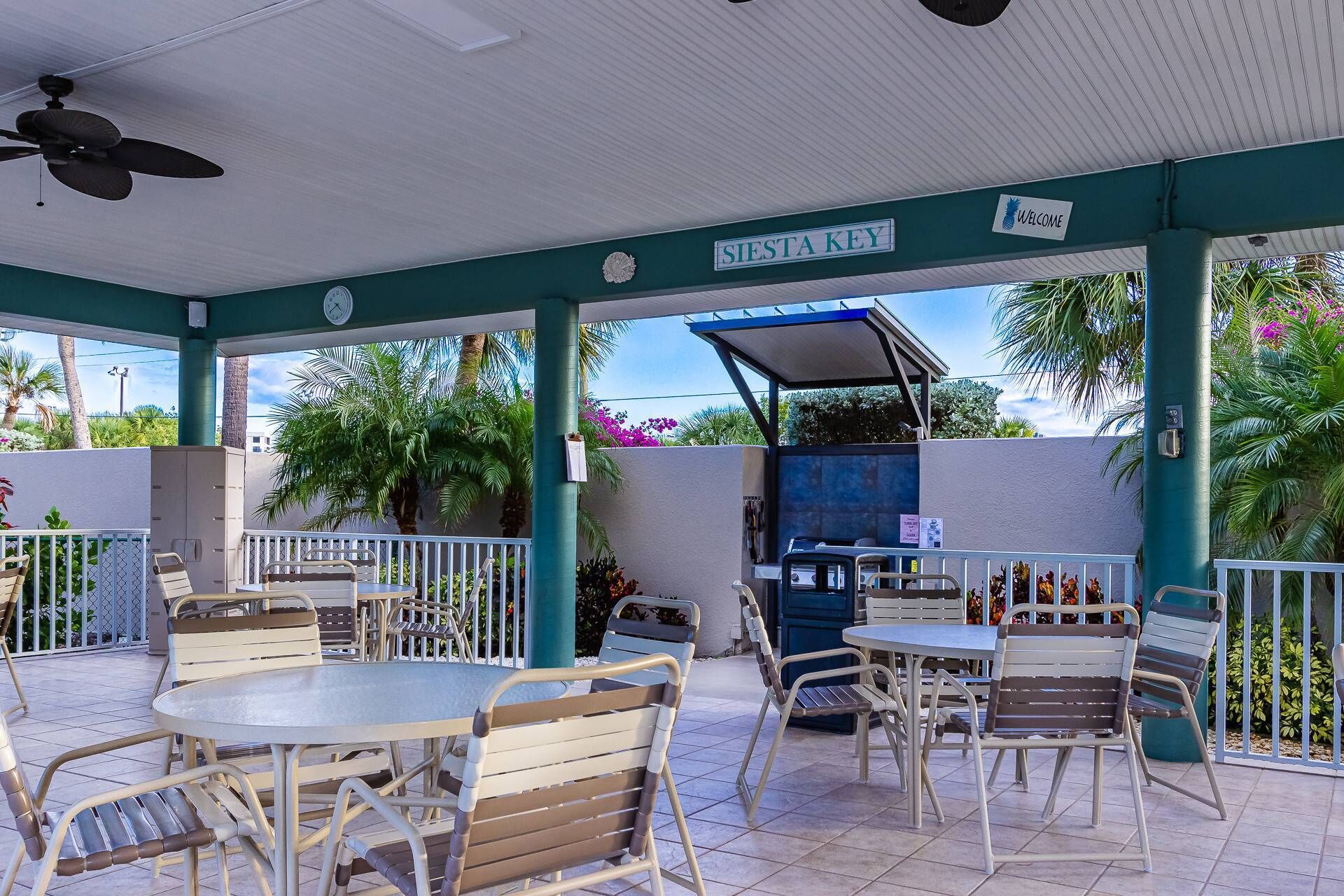 An outdoor patio area with tables and chairs, a barbecue grill, and a sign reading "Siesta Key".