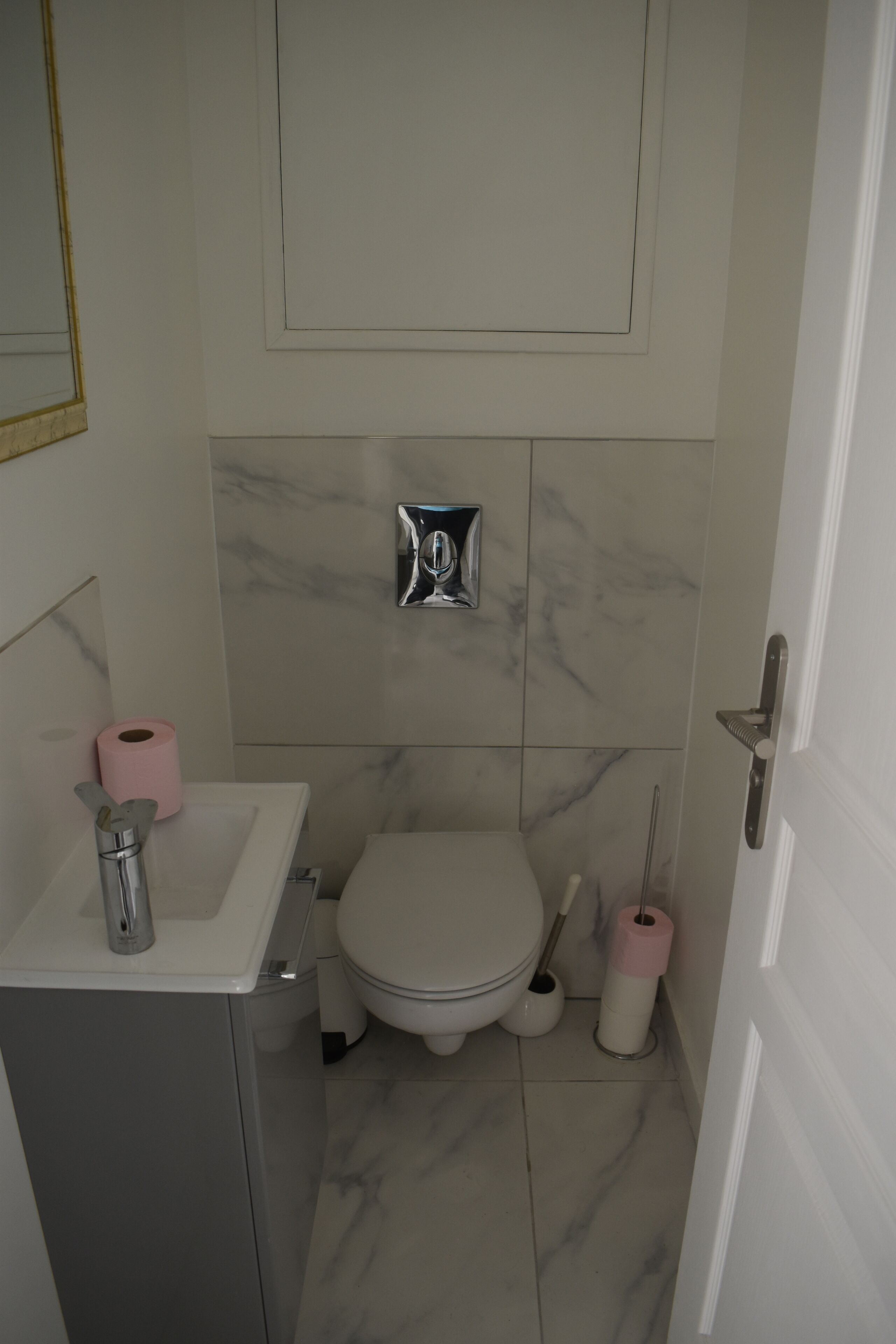 A compact bathroom with a white sink, a toilet, and a shower area.