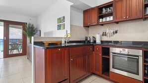 Une cuisine avec des meubles en bois, un four en acier inoxydable et un plan de travail noir.