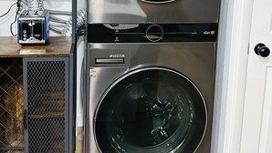 A stacked washer and dryer unit with a control panel, a small shelf with kitchen items, and a door with a handle. - Home sweet home in West Jordan (West Jordan)