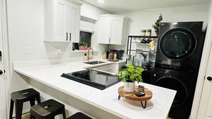 A modern kitchen with white cabinetry, a black refrigerator, and a central island with stools. - Home sweet home in West Jordan (West Jordan)