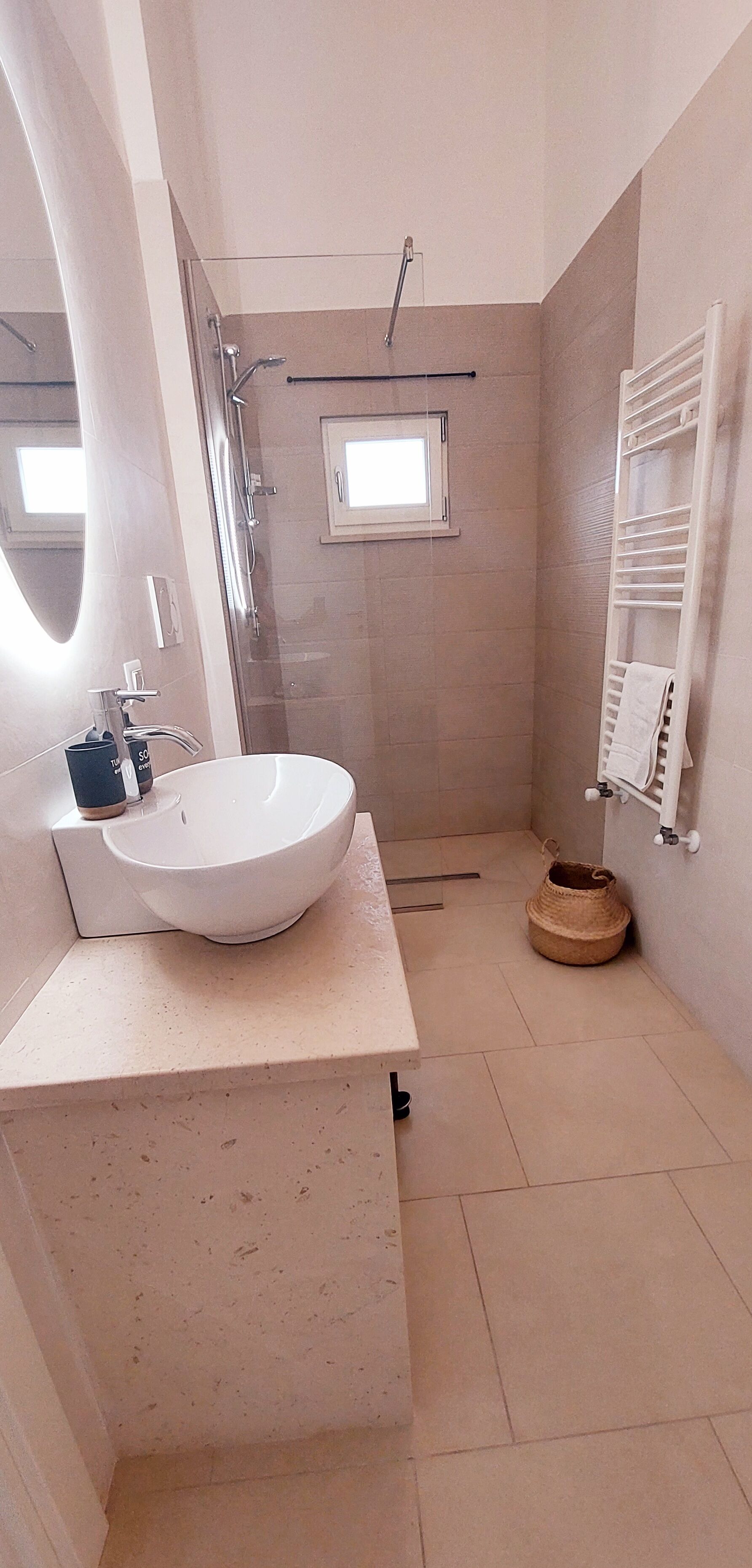 Un bany modern amb un lavabo gran, un espai de banyera amb envidriament i una finestra petita.