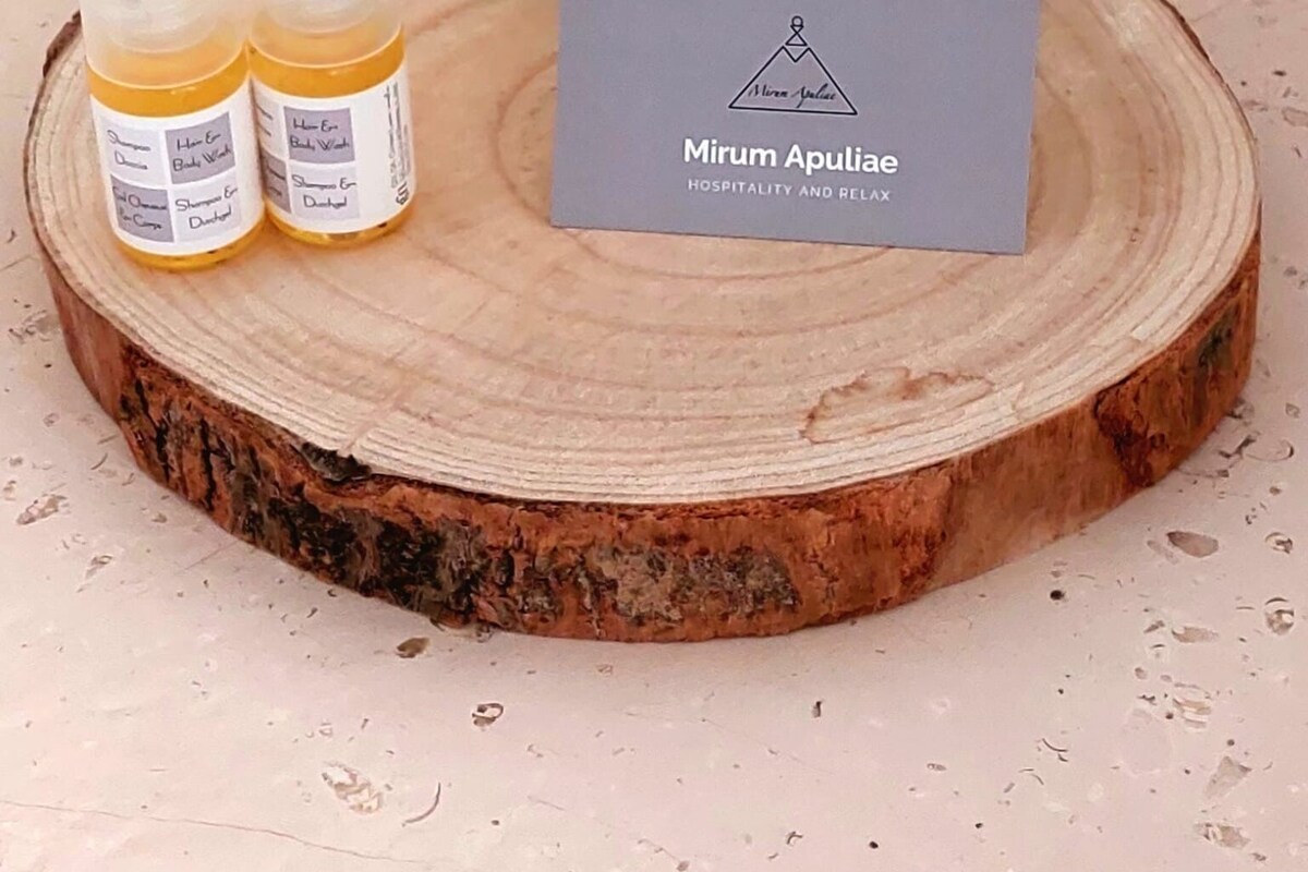Una làmina de fusta amb dues ampolles de xampú i una espelma sobre una taula.
