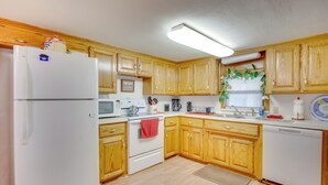 A kitchen with wooden cabinets, a white refrigerator, a microwave, a coffee maker, and a sink. - Cozy Fort Cobb Home Rental Near Lake Access! (Fort Cobb)