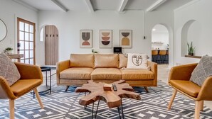 Ein modernes Wohnzimmer mit einer Ledersofa, einem gemusterten Teppich und abstrakter Wandkunst.