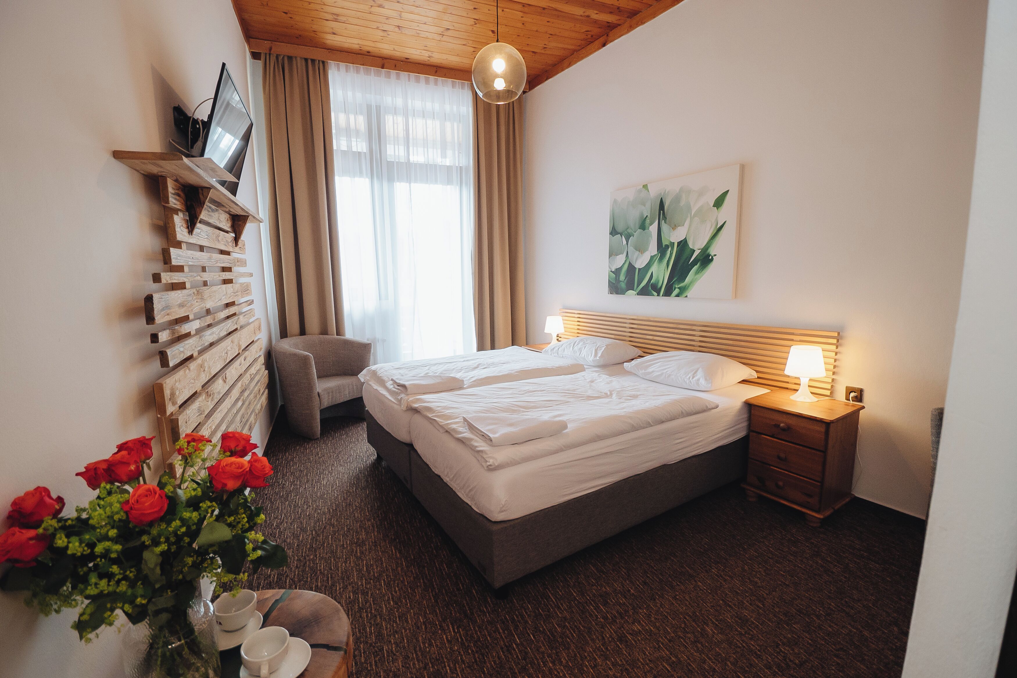 A neatly arranged bedroom with a bed, bedside table, and a wall-mounted TV.