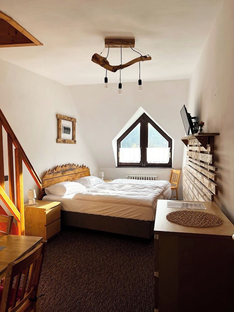 Un dormitorio con cama, cabecera de madera, ventana, escritorio y silla.