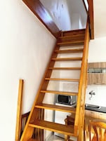 A wooden staircase leading to a kitchen area with a microwave on the counter.