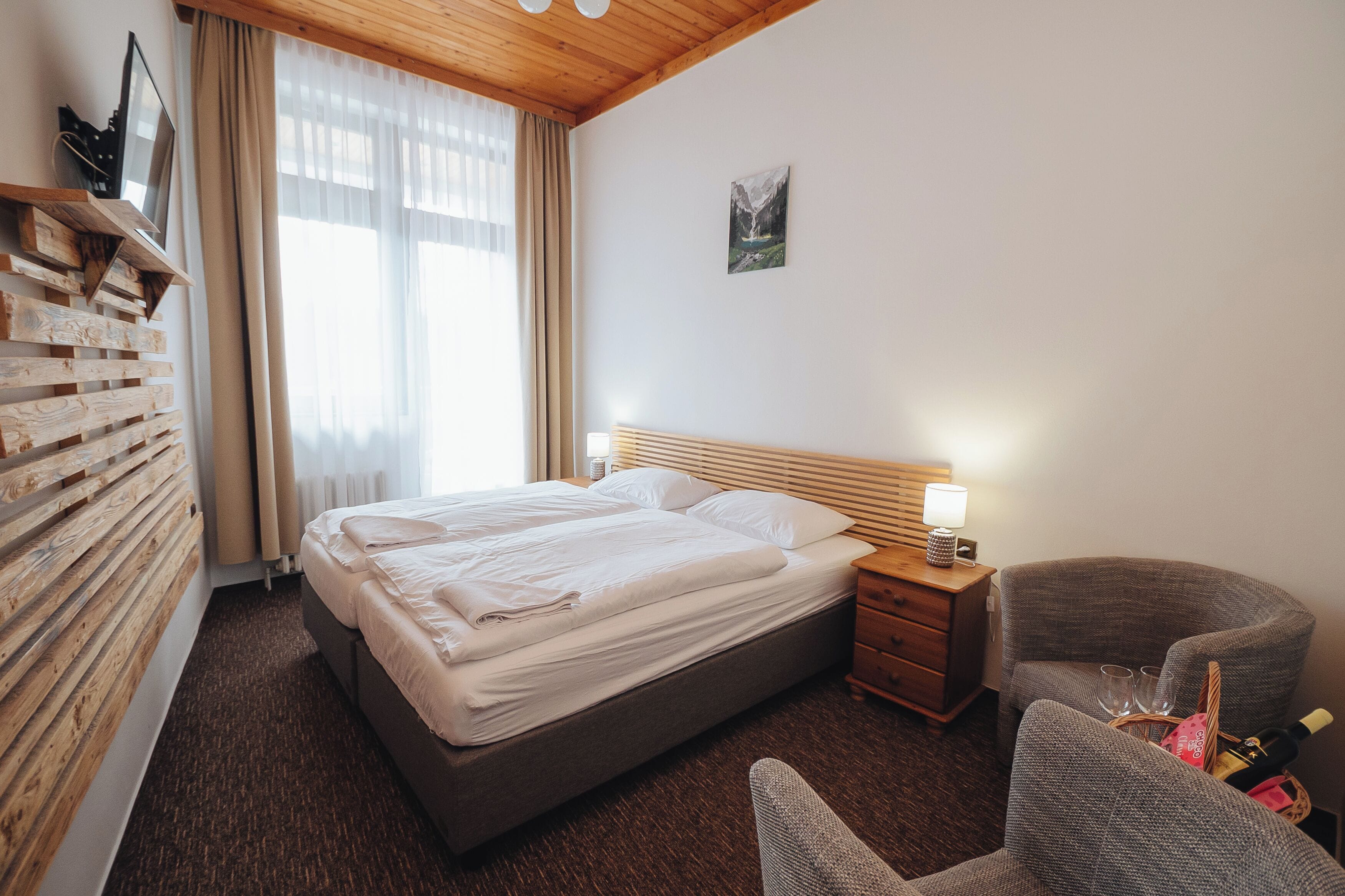 A neatly arranged hotel room with a bed, bedside table, and a chair.