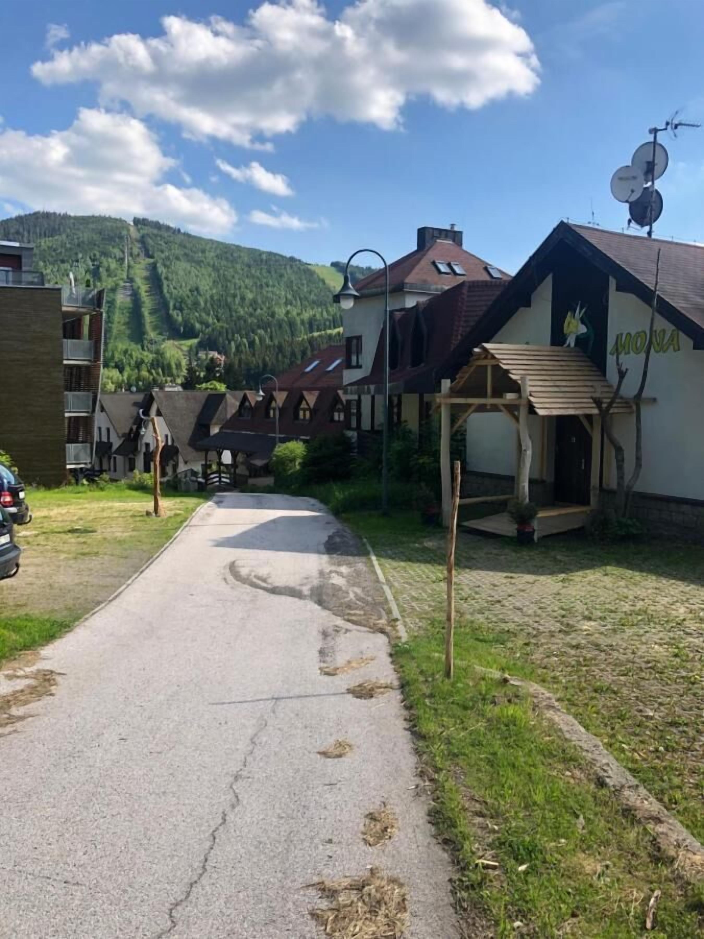 A street with buildings, a clear sky, and a mountain in the background.