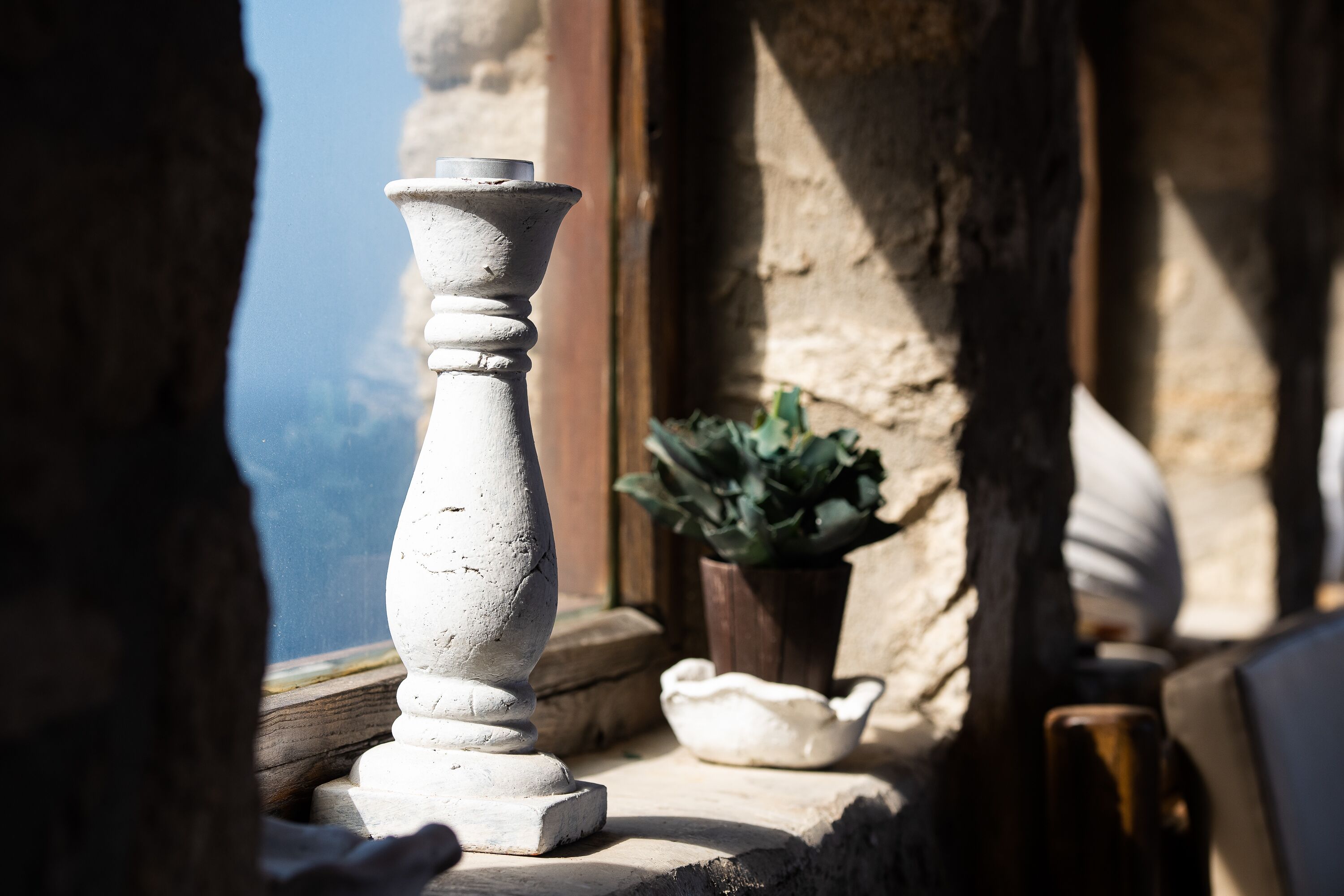 A stone balustrade with a potted plant and a small bowl on a ledge.