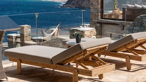 Una terraza con sillones de madera y vista al mar.