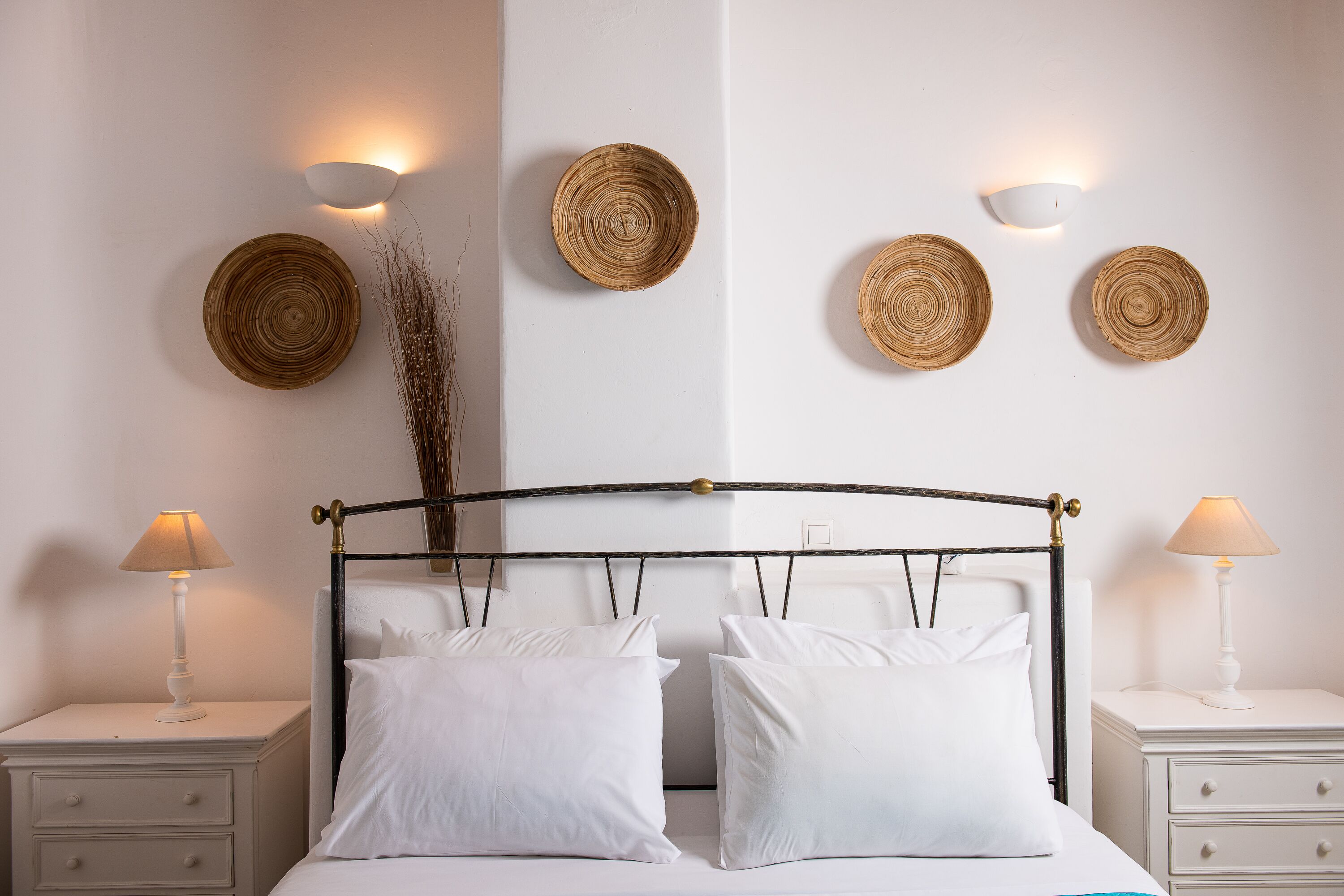 A bedroom with a bed, two bedside tables, and wall-mounted light fixtures.