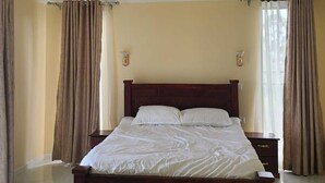 A spacious bedroom with a large bed, a ceiling light fixture, and curtains on the windows. - Astrahill Villa,  A Royal Gateway near Ngong Hill. Nairobi (Kajiado County)