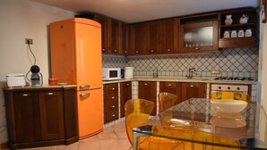 Una cucina con mobili in legno, un tavolo in vetro e una sedia gialla.