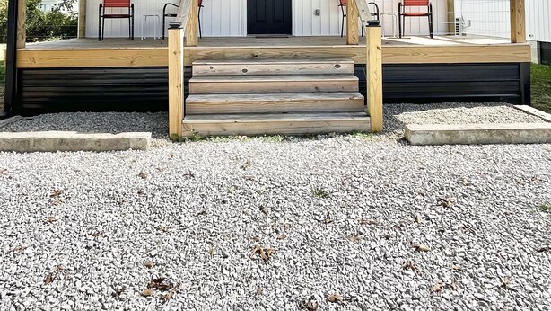 A modern building with a covered porch, a black door, and two red chairs. - Cottage at Cave Run  (Salt Lick)