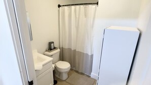 A compact bathroom with a toilet, sink, and shower curtain. - Cottage at Cave Run  (Salt Lick)