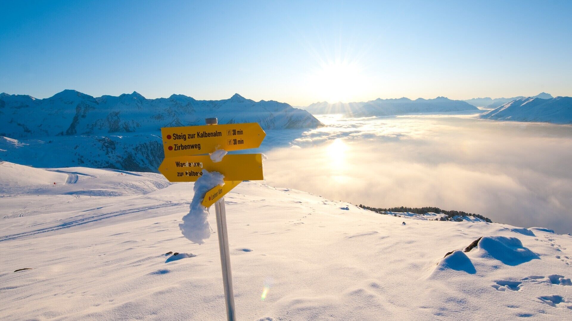 A snow-covered mountain landscape with a signpost indicating directions to various locations.