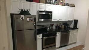 Una cocina moderna con electrodomésticos de acero inoxidable, armarios blancos y suelo de madera.
