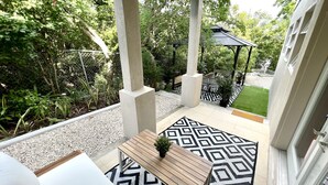 A covered patio with a geometric patterned rug, a small wooden table, and a potted plant. - CAICOSVERDE Amazing Garden 2 Bedrooms Suite with Living Room and Kitchenette. (Providenciales)