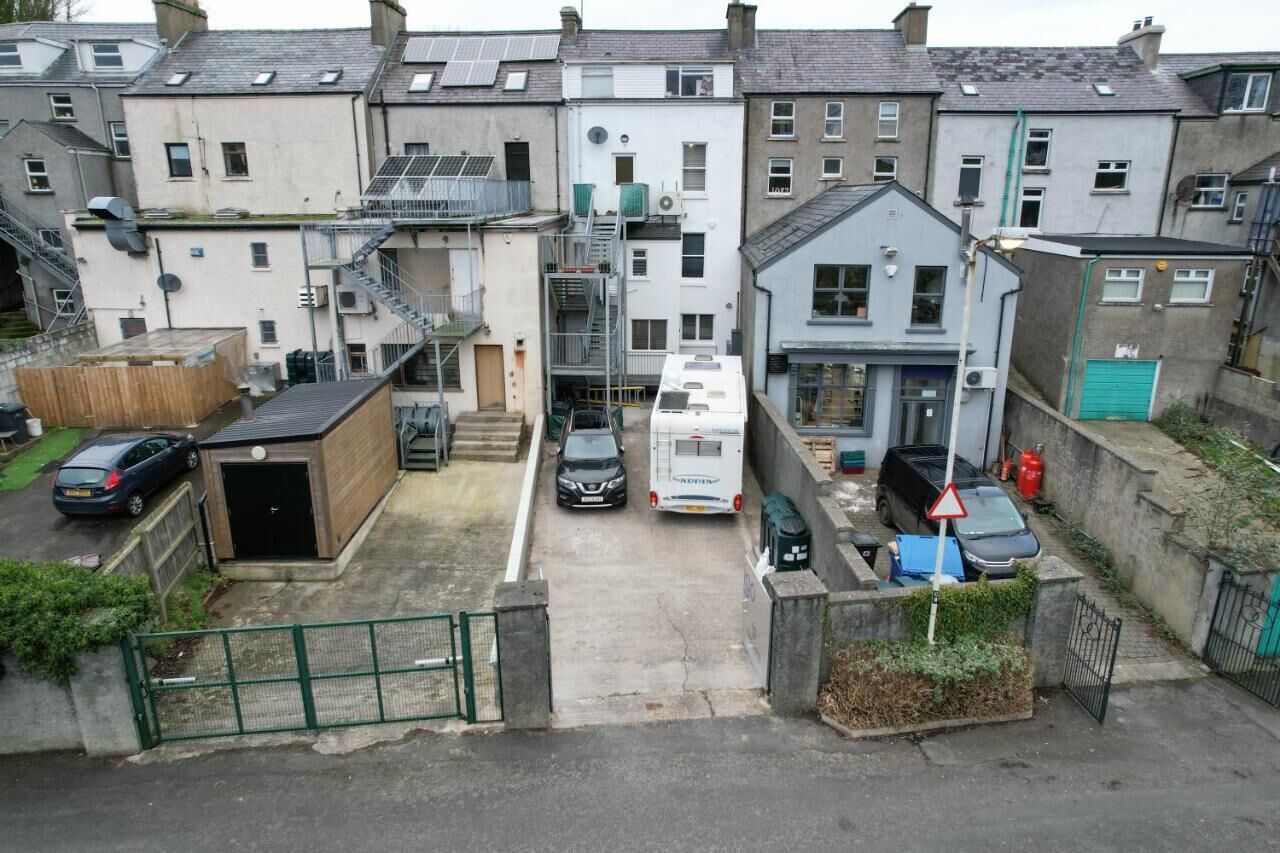 Un quartier résidentiel avec une rue étroite, des voitures garées et un camping-car blanc.