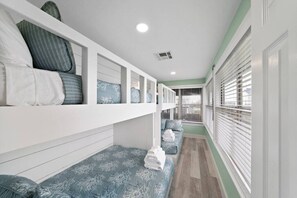 A narrow hallway with a bunk bed on the left and a bench on the right. - Waterfront Canal Home with Pool & Fishing Access (Galveston)