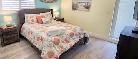 A bedroom with a bed, nightstands, a lamp, a painting, and a window.