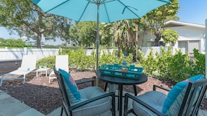 An outdoor patio with a round table, two chairs, and a large blue umbrella.