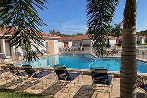 A swimming pool with lounge chairs and palm trees.