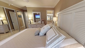 A spacious bedroom with a large bed, a dresser, a vanity, and a television. - White Sands & Ocean Waves Bld 5 2nd fl (Siesta Key)