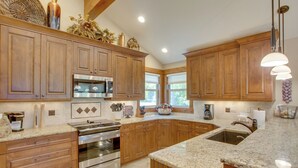 A kitchen with wooden cabinets, granite countertops, stainless steel appliances, and a large island with a sink. - Avon Duplex Between Beaver Creek & Vail Resorts! (Avon)