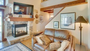 A cozy living room with a stone fireplace, leather sofa, and wooden beams. - Avon Duplex Between Beaver Creek & Vail Resorts! (Avon)